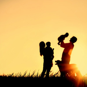 Family with dog, toddler and baby enjoying family time at sunset