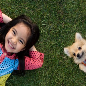 Cute kid and her dog relaxing on a green lawn