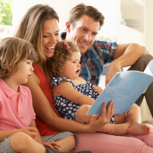 Family of four reading a book together